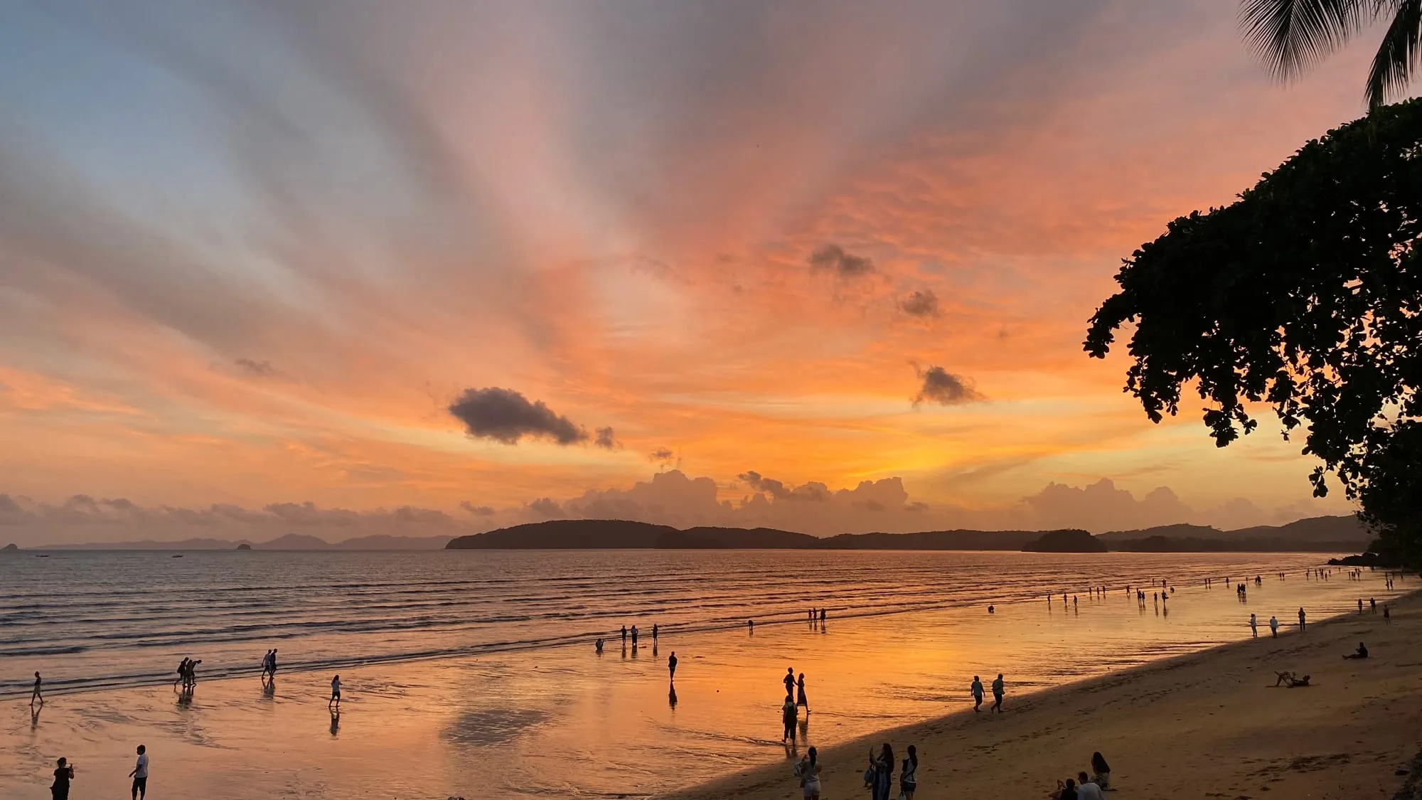 Golden-hour sunset over Ao Nang Beach with longtail boats and limestone cliffs, Krabi — steps from The Hub Laidback Hostel