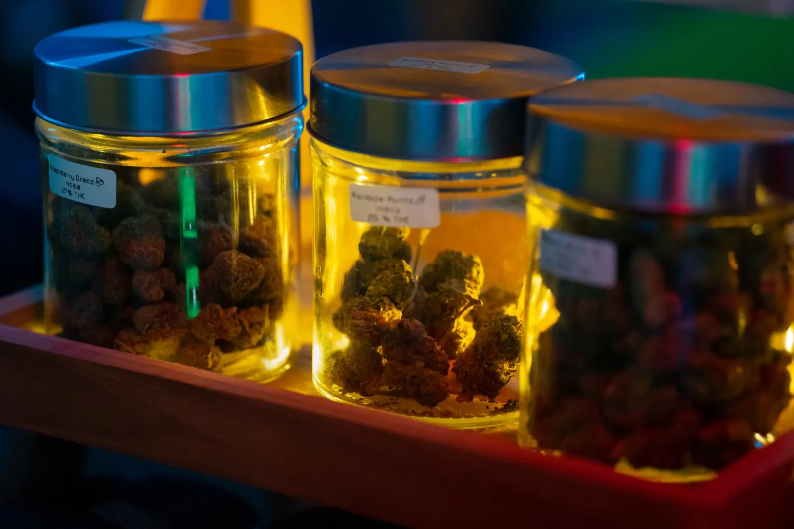 Glass jars of cannabis flower glowing under warm light at The Hub, Ao Nang